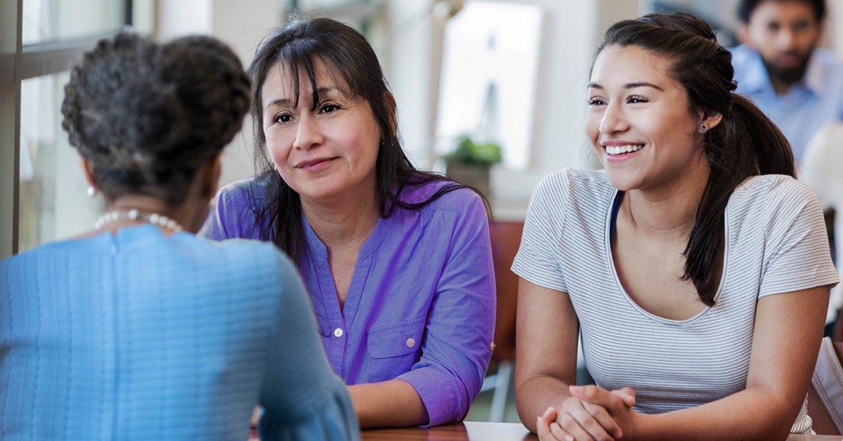 Photo of three women around a table talking