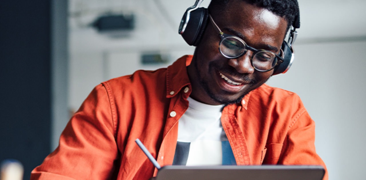 Photo of a student wearing headphones and working at a tablet