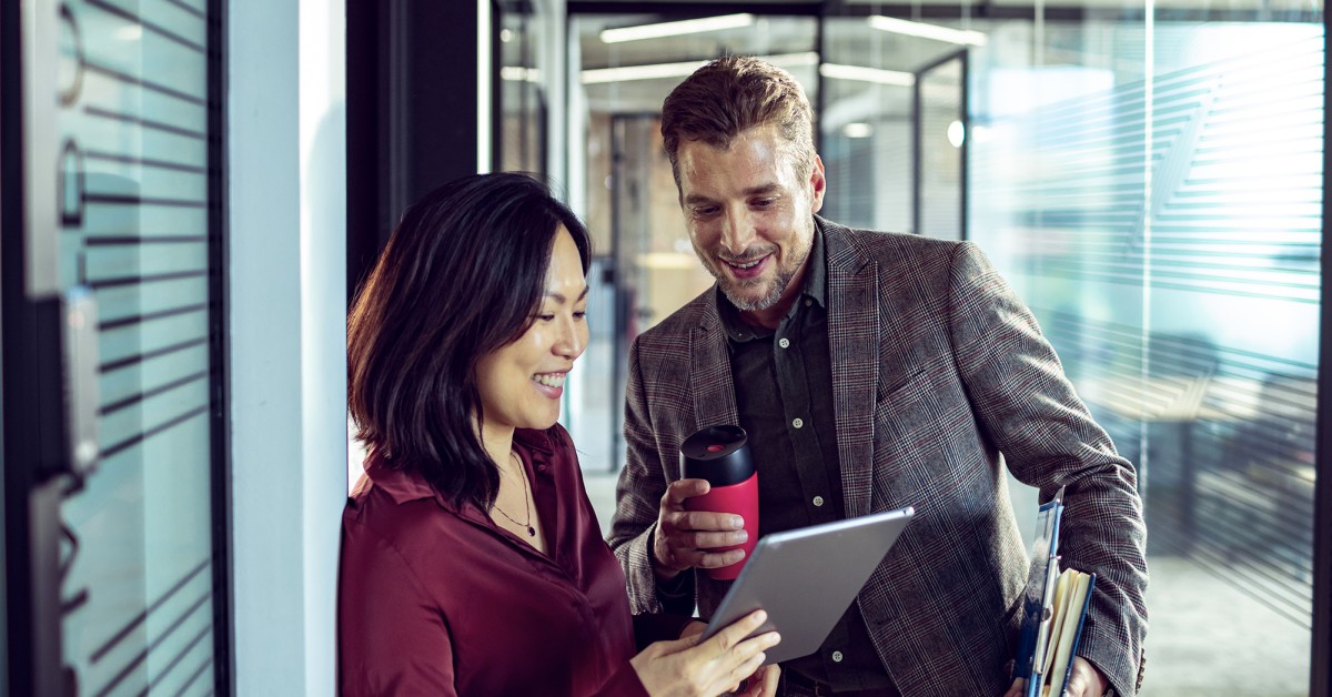 Photo of two people talking while looking at a tablet