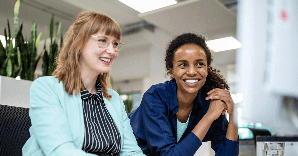 Coworkers smiling and working on a computer together